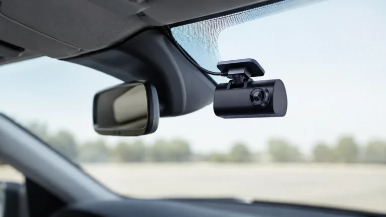 Dash camera mounted on a vehicle windscreen beside the rear-view mirror